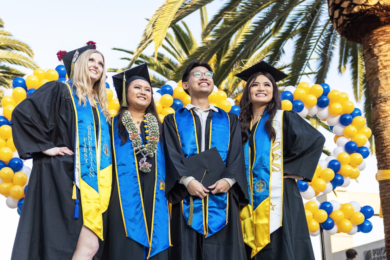 A group of San José State University graduates pose for a photo dressed in their graduation cap and gown.