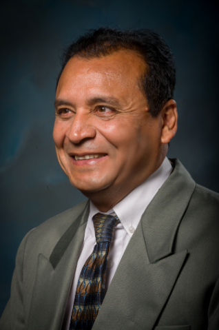 headshot of Harish Chander in gray blazer and blue backdrop